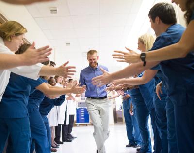 Missionary Dr Brantly is cheered by colleagues as he walks out of hospital free from any traces of the virus in his body
