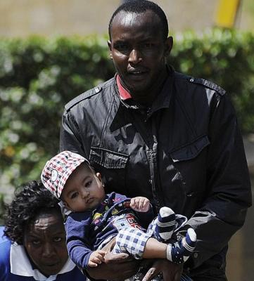 A Kenyan police officer carries a baby to safety - Photo NYDailyNews